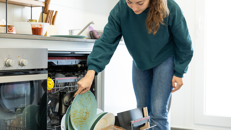 A woman places dirty dishes in the dishwasher