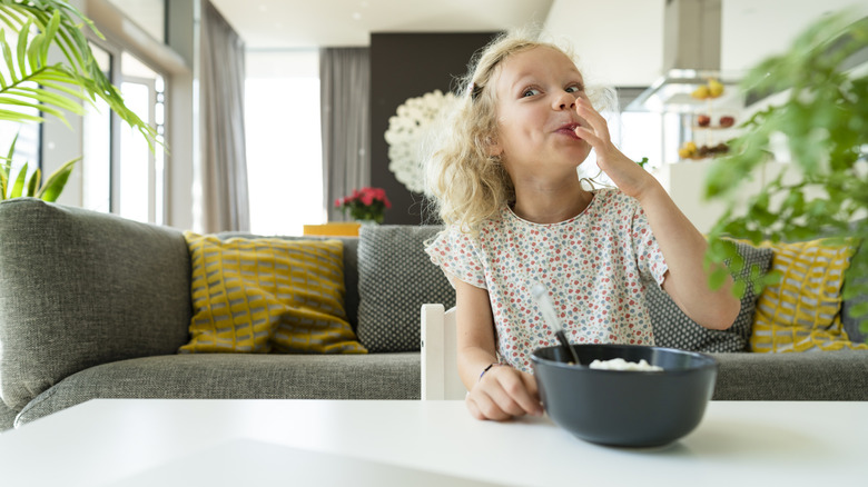 A little girl eats a snack in the living room