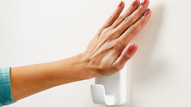 A person pushing a Command Hook against the wall