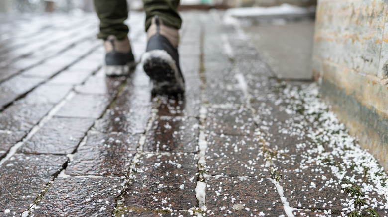 Close up of person walking on icy sidewalk with dry rock salt