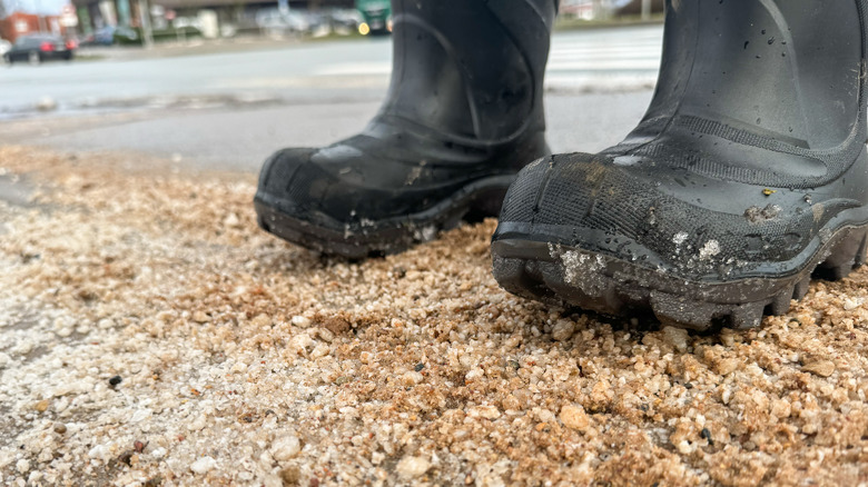 Close up of boots on sand-covered ice