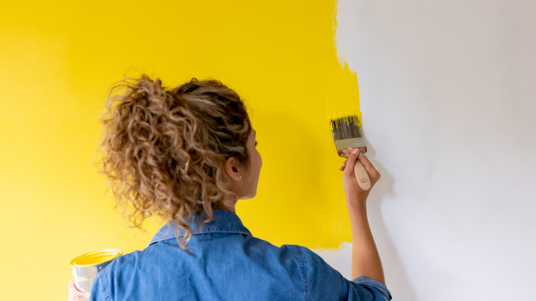 Woman painting yellow wall