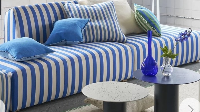A blue striped couch with striped pillows.