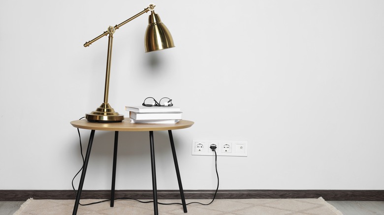 gold finish industrial lamp on side table with books and glasses