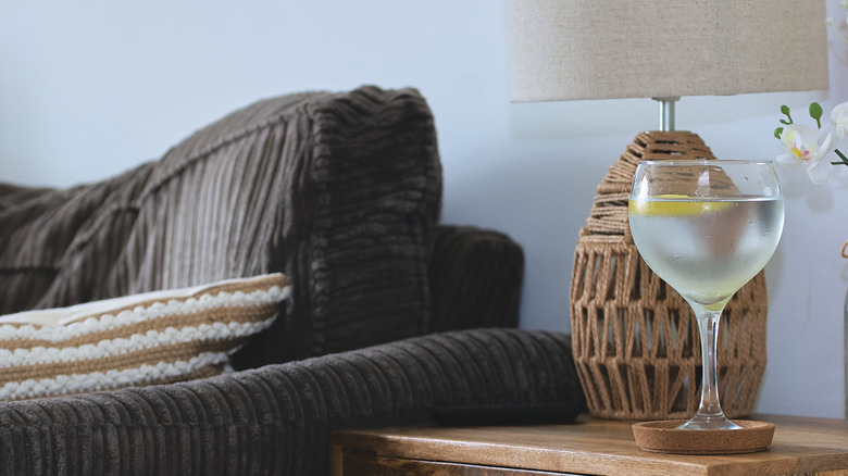 End table with drink on coaster and tall lamp