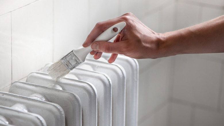Person painting the top of a radiator with white paint