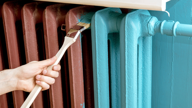 A person painting a radiator turquoise