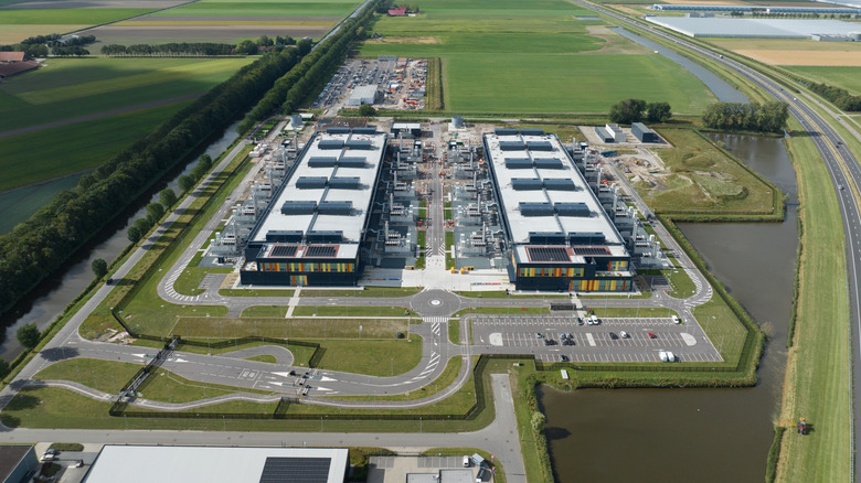 An aerial view of two large rectangular data centers surrounded by parking lots in the middle of an otherwise green field