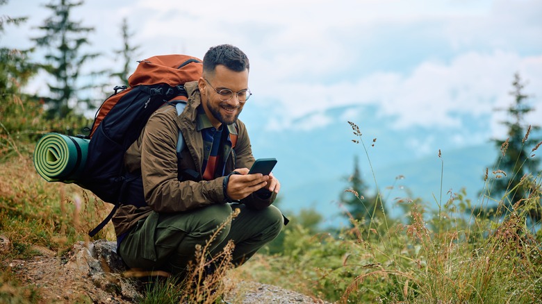 Male backpacker viewing mobile phone on hike