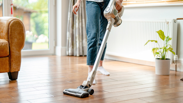 A person vacuuming hardwood floors
