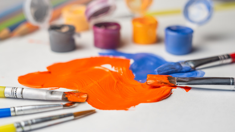 Orange and blue paint surrounding by small paintbrushes.