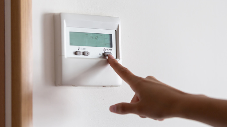 A person adjusts their home thermostat