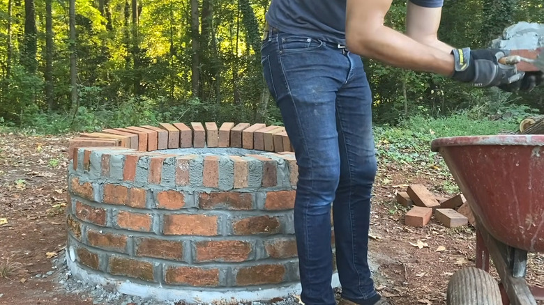 a DIYer makes a brick fire pit in the backyard
