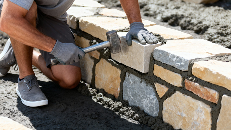 Person building a short retaining wall out of stone