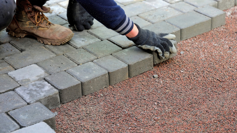 Person placing small pavers on a bed of gravel