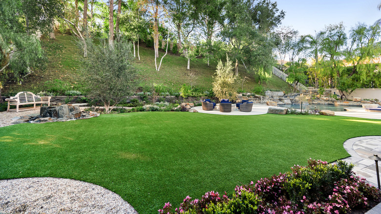 A backyard with pathways, patios, and synthetic turf