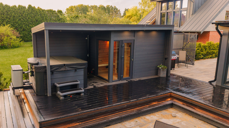 A backyard deck with a sauna and a hot tub