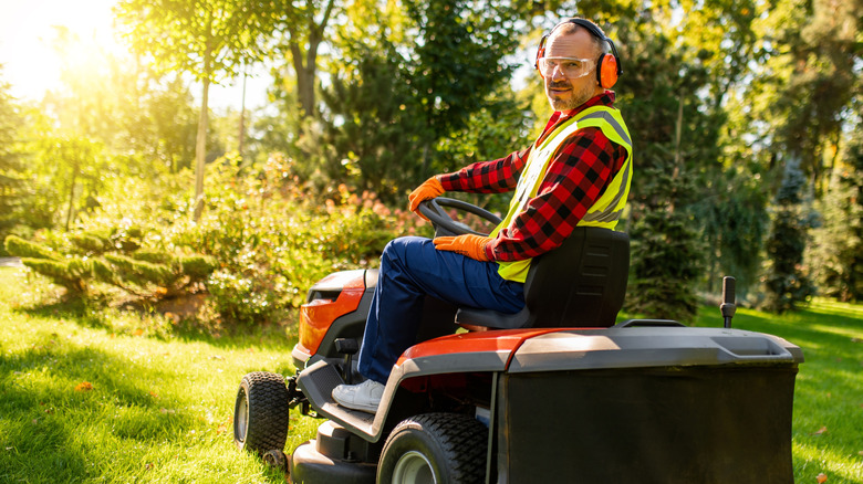 Person wearing appropriate clothing and safety gear on riding mower