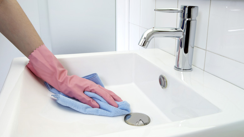 Woman wiping a porcelain sink with a microfiber cloth