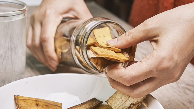 someone placing banana peels in a jar to make fertilizer