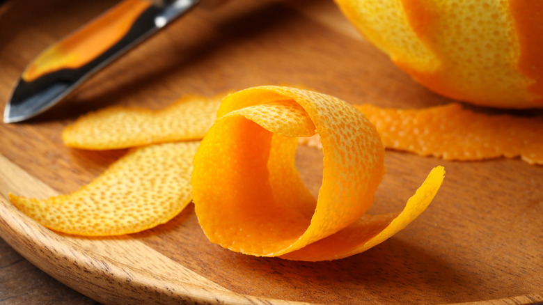 Orange peels on a wooden cutting board with a knife