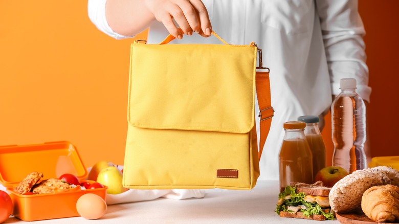 Person holding yellow lunchbox