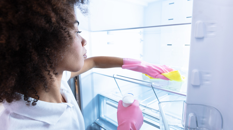 woman cleaning fridge interior