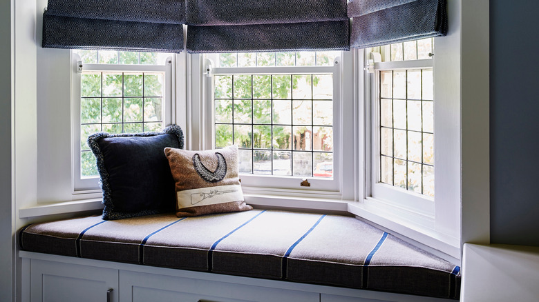 Stylish banquette seating in bay window of home featuring storage cabinets on the bottom