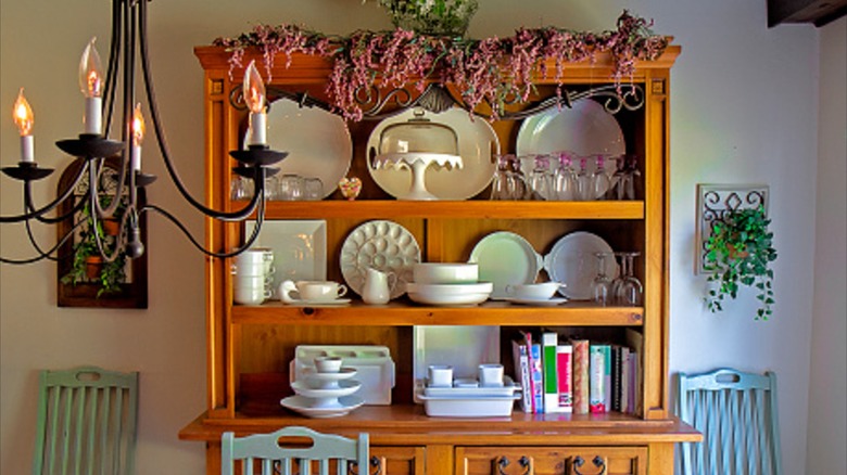 Hutch in a dining room with serving dishes and cook books on it.