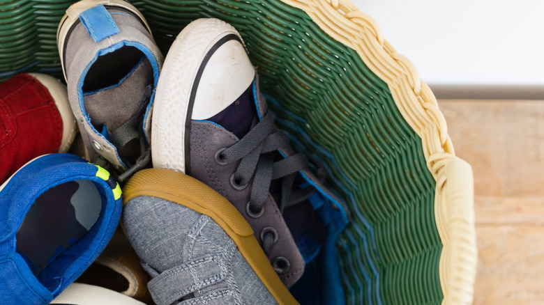 Children's shoes in a green wicker basket with a tan rim