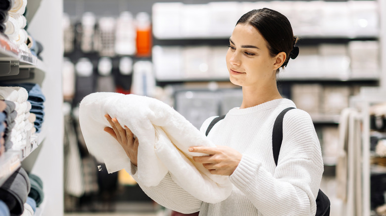 A woman looking at a white towel in the store.