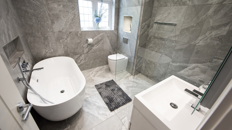 Grey bathroom with white bathtub, sink, and floor