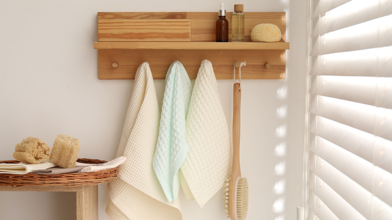 towels hanging on a hook rack with spa products on the shelf
