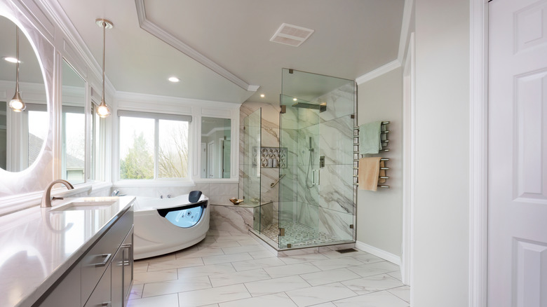 spacious contemporary bathroom with statement mirrors and a heated towel rack