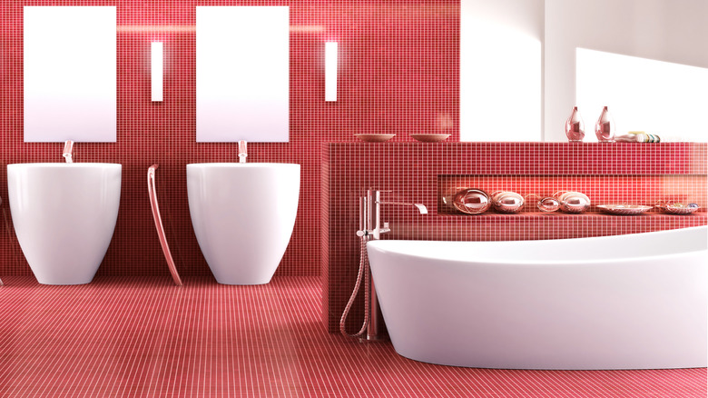 A bathroom covered in red tile with a white bathtub and white sinks