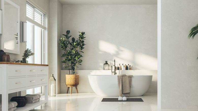 A modern bathroom with a bathtub and light coming in through a window