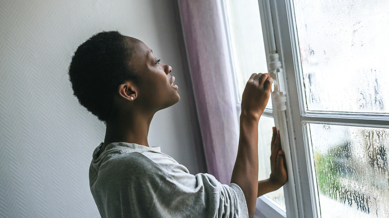 Woman opening a window in her home