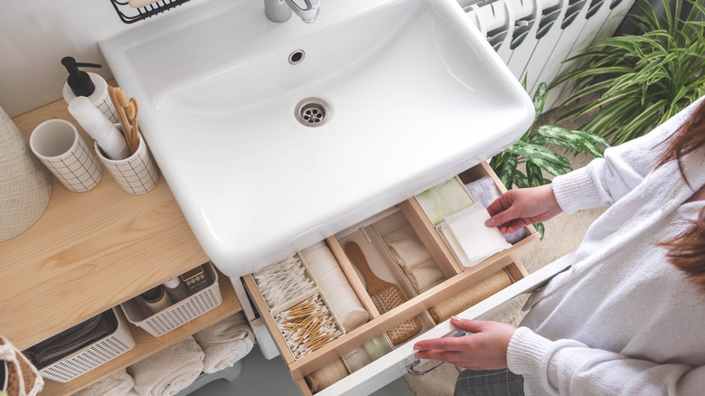 Woman opening two drawers in a bathroom