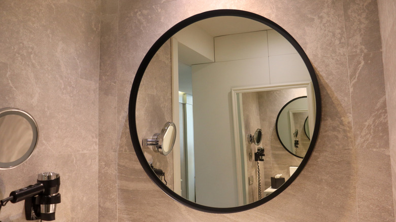 A round mirror with a black edge in a bathroom