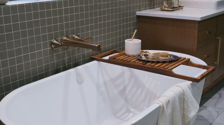 A bathtub against a green tiled wall