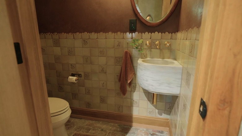 A sink and mirror against a cream and brown colored wall
