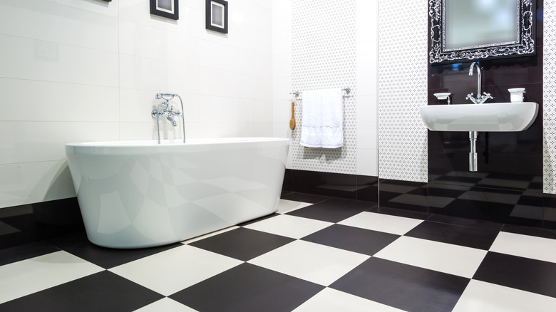 Checkerboard tiled floor in black and white with stand-alone tub