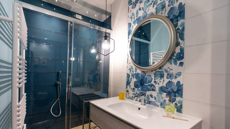 Painted flower tiles behind a mirror in a blue and white bathroom