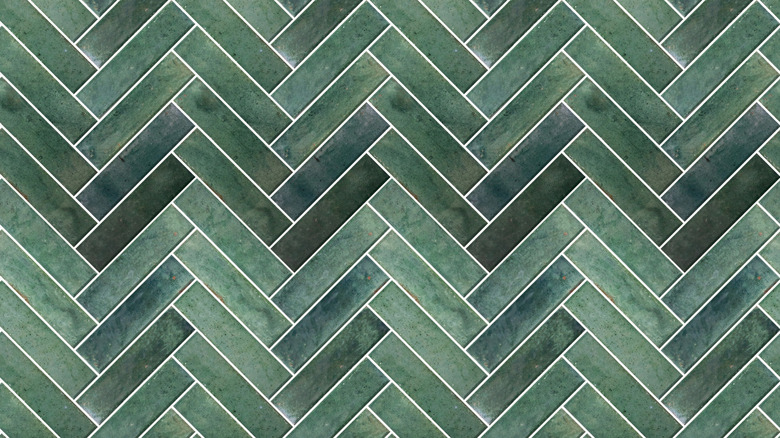 green rectangular tiles arranged in a herringbone battern with white grout