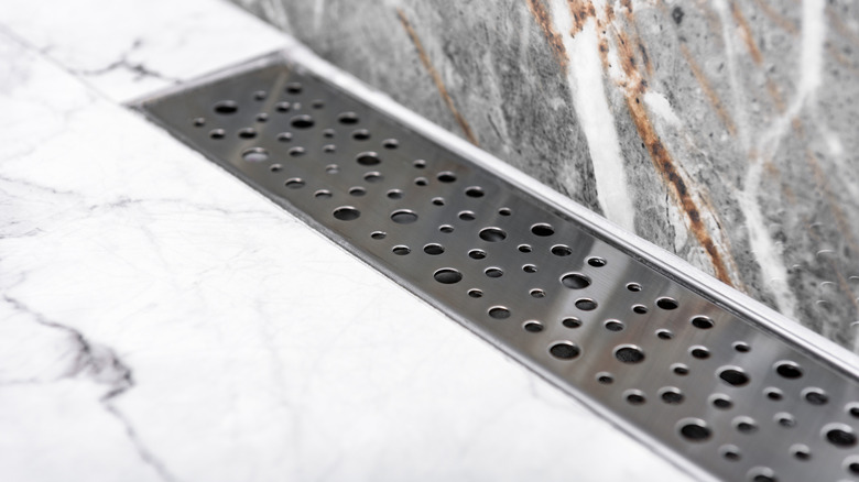 A decorative stainless steel linear drain in a shower