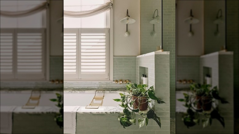 Lovely bathroom with a tub and a window behind it with shutters for privacy
