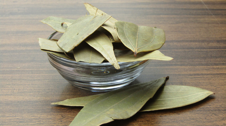 Dry bay leaves in a small glass bowl on a table