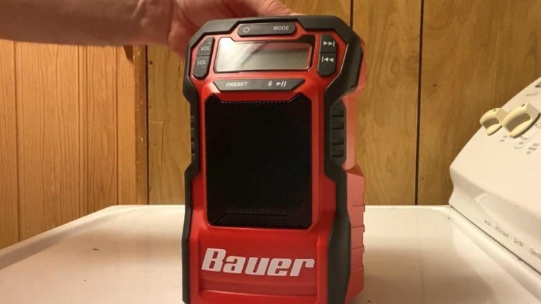 man's hand behind cordless BAUER compact radio on washing machine