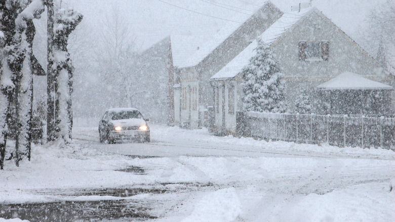 car driving through town during winter storm