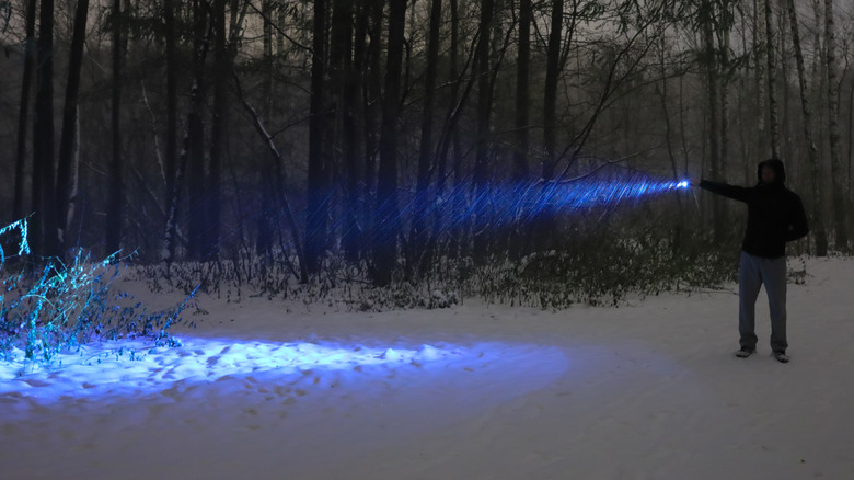 man holding flashlight in snow